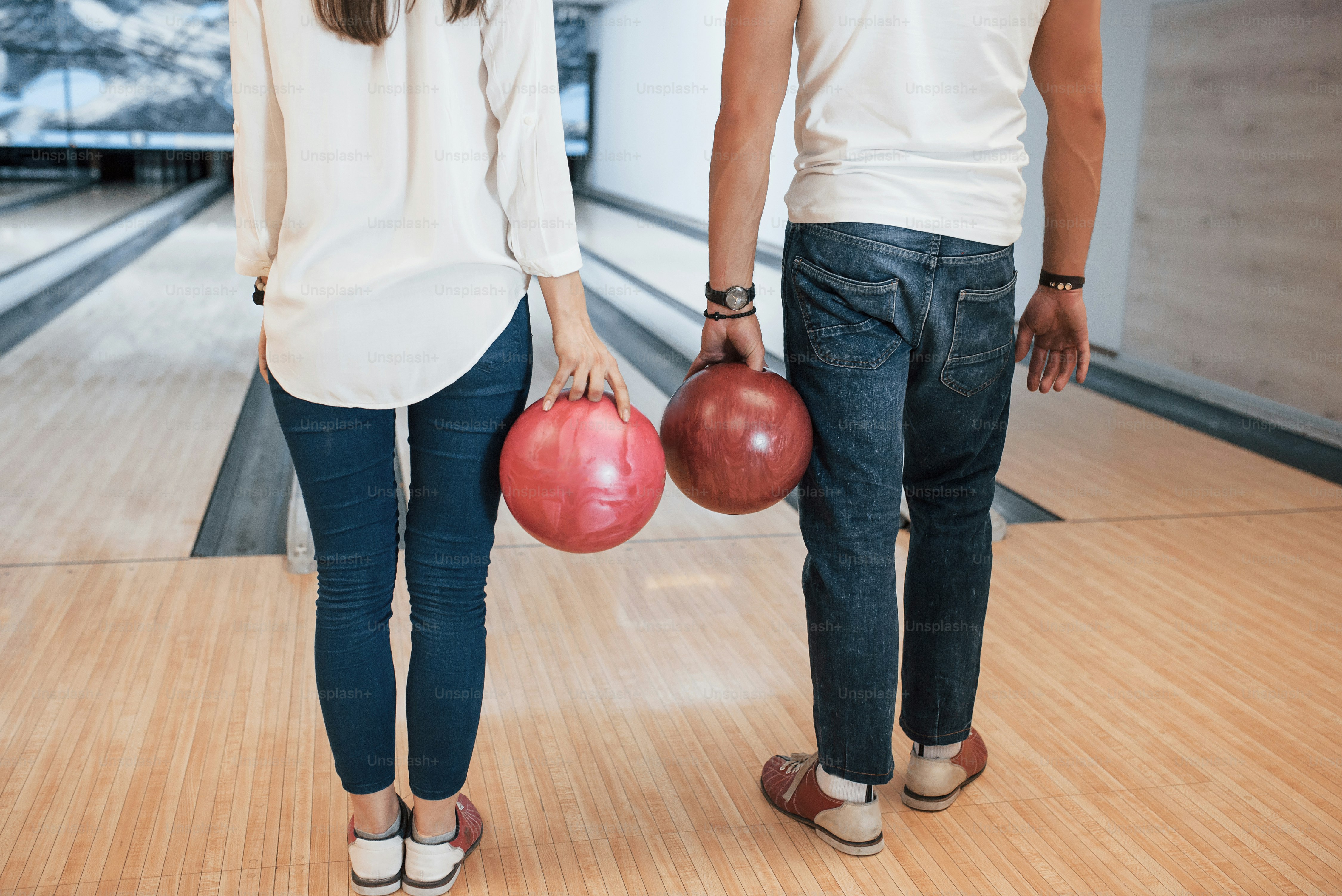 In jeans and white shirts. Cropped view of people at the bowling club ready to have some fun.
