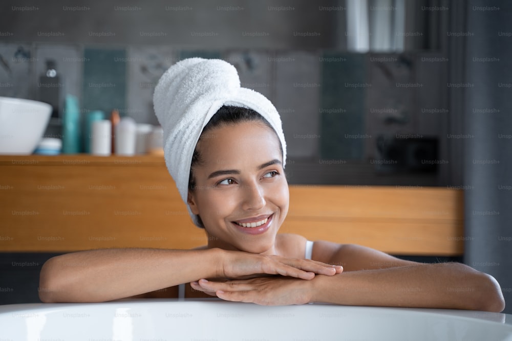 Ritratto ravvicinato di una bella giovane donna sorridente appoggiata sul bordo della vasca da bagno