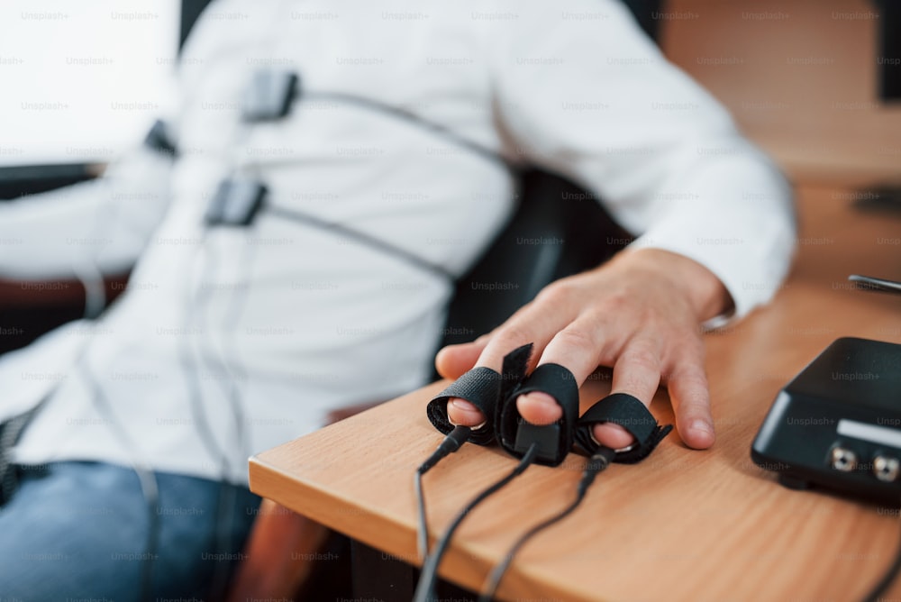 指に電極。不審な男がオフィスでうそ発見器を通過します。質問する。ポリグラフテスト。
