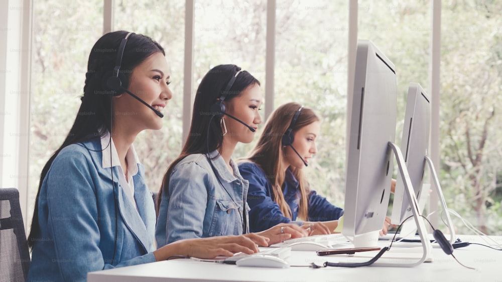 Customer support agent or call center with headset works on desktop computer while supporting the customer on phone call. Operator service business representative concept.