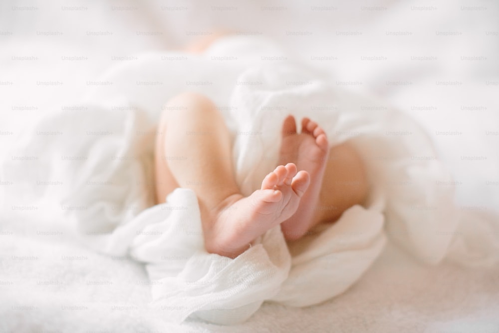 Newborn little baby legs on furry cloth wearing white headband