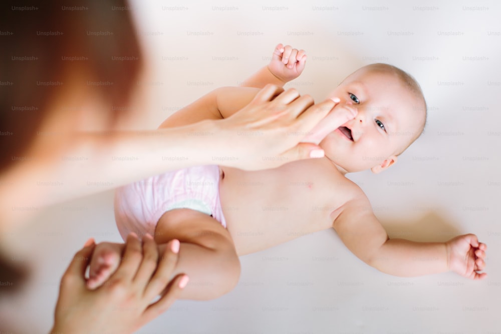 Massagem para bebês. Mãe massageando e fazendo ginástica com as pernas do filho.