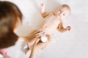 Mother preparing baby powder in her hand and four month old baby as a background.