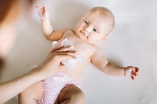 Hygiene - junge Momy wischt die Babyhaut mit feuchten Tüchern ab. Reinigungstuch, rein, sauber.