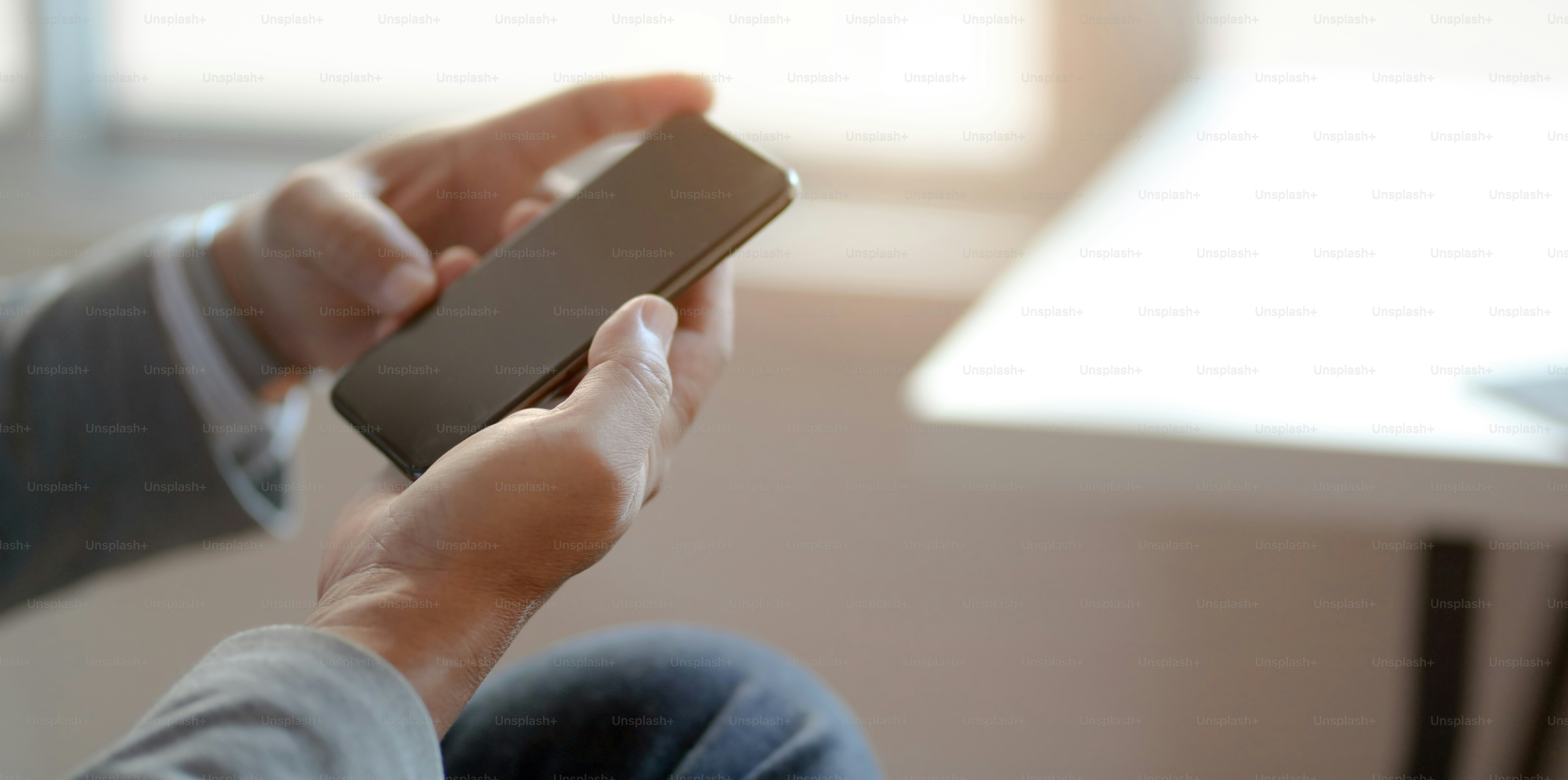 Close-up view of professional businessman looking at his smartphone while working at his workplace