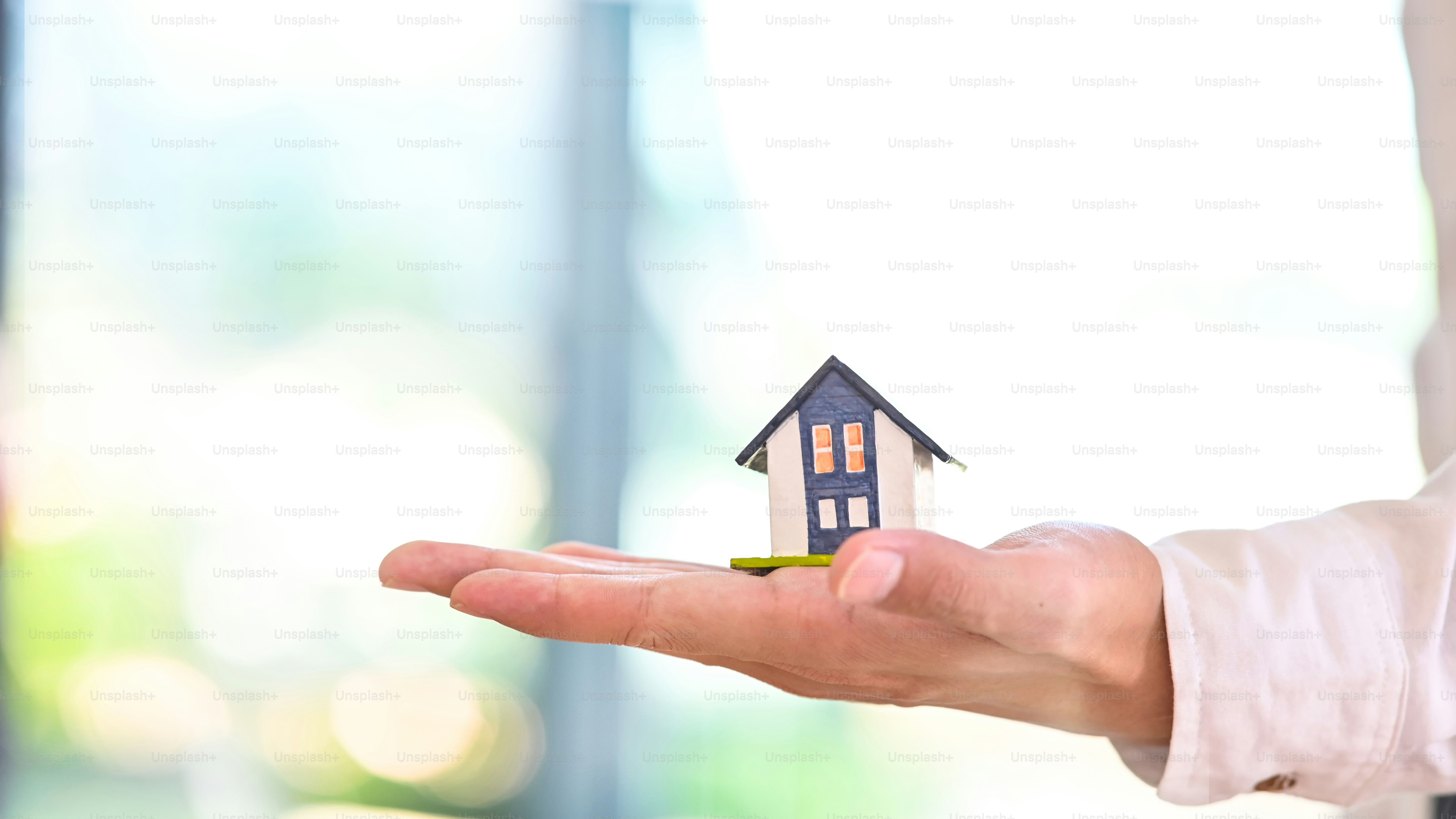 Vista lateral de una maqueta de casa en una mano.