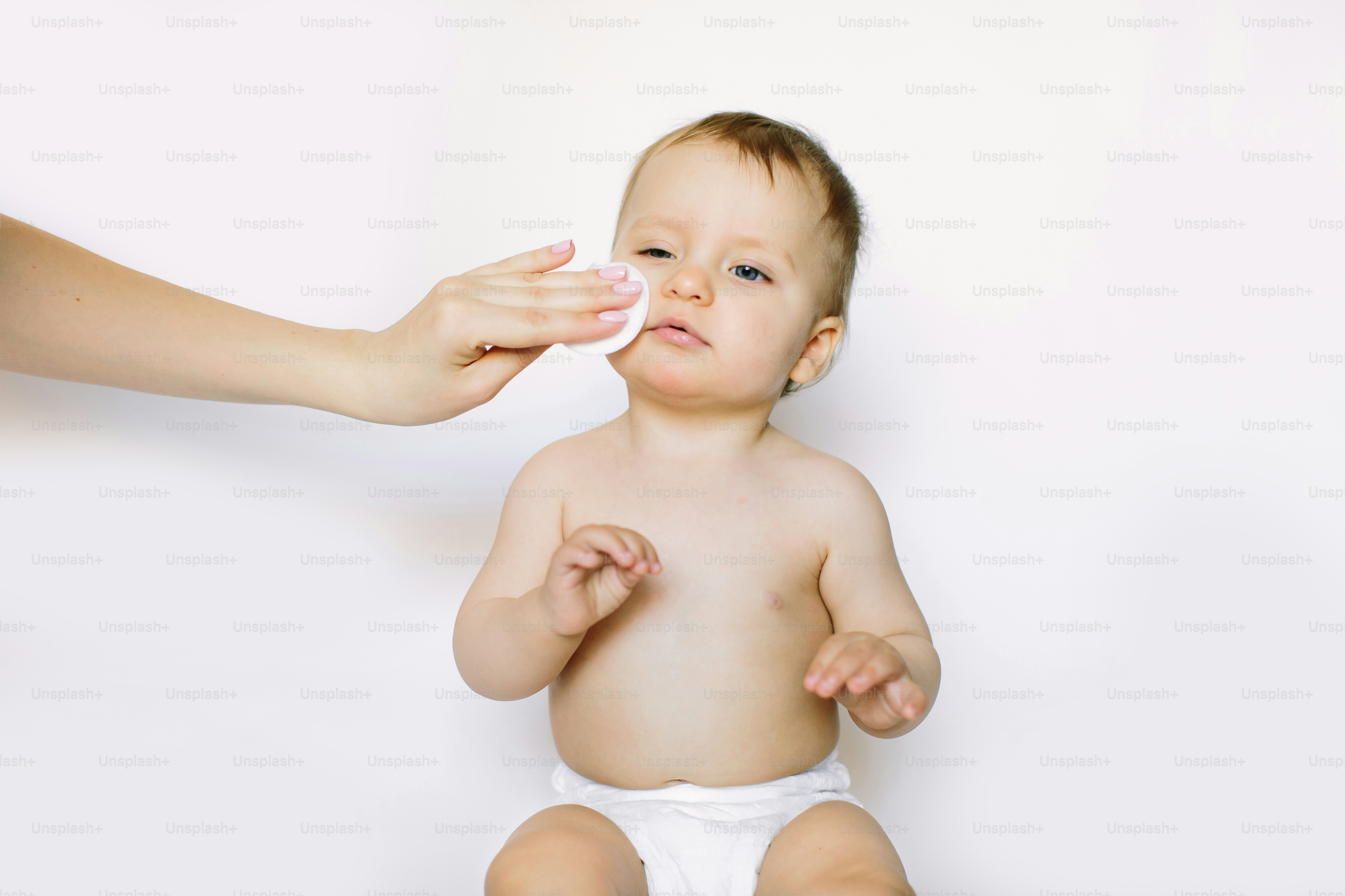 A mother cleaning baby skin, isolated on white background.