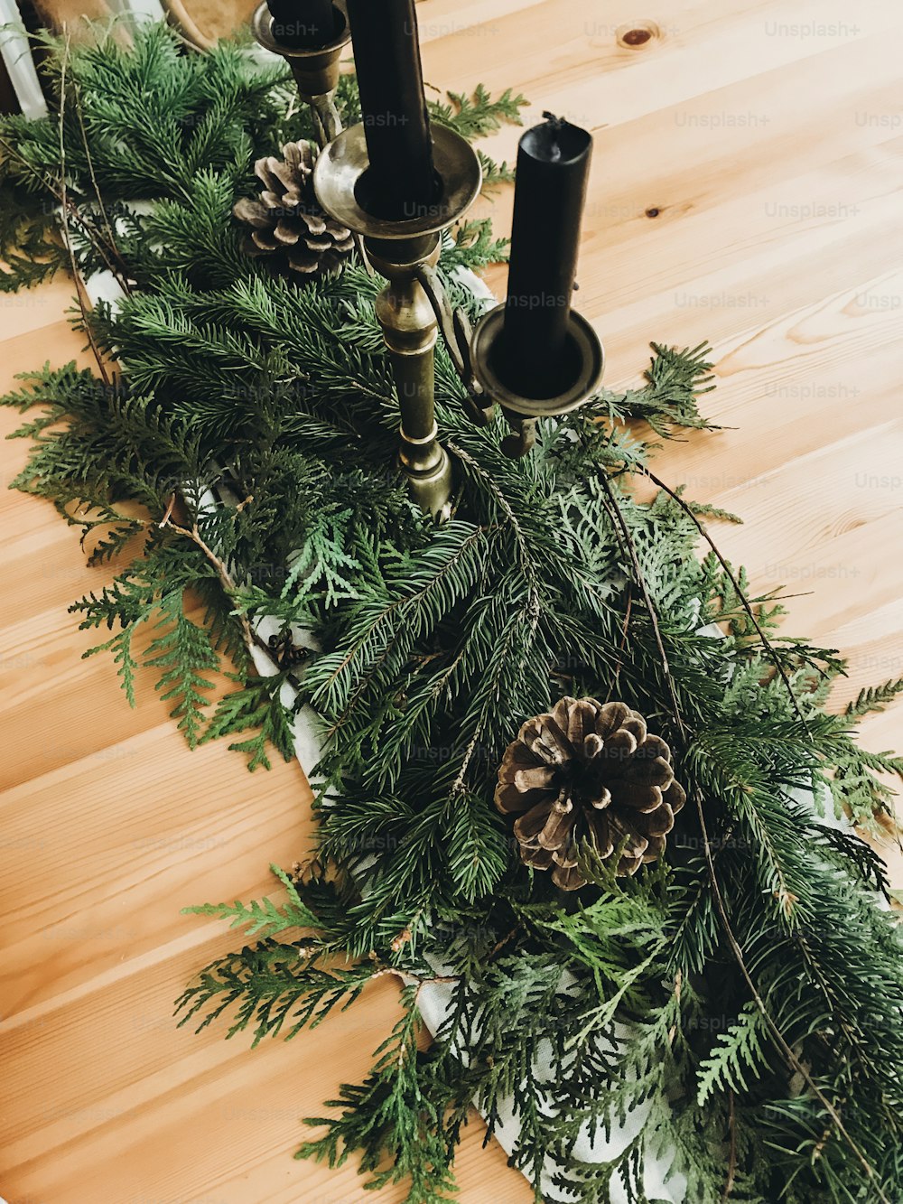 Christmas rustic decor of table. Vintage candlestick,pine branches with cones on wooden table, festive arrangement. Rural holiday decoration. Happy holidays. Phone photo