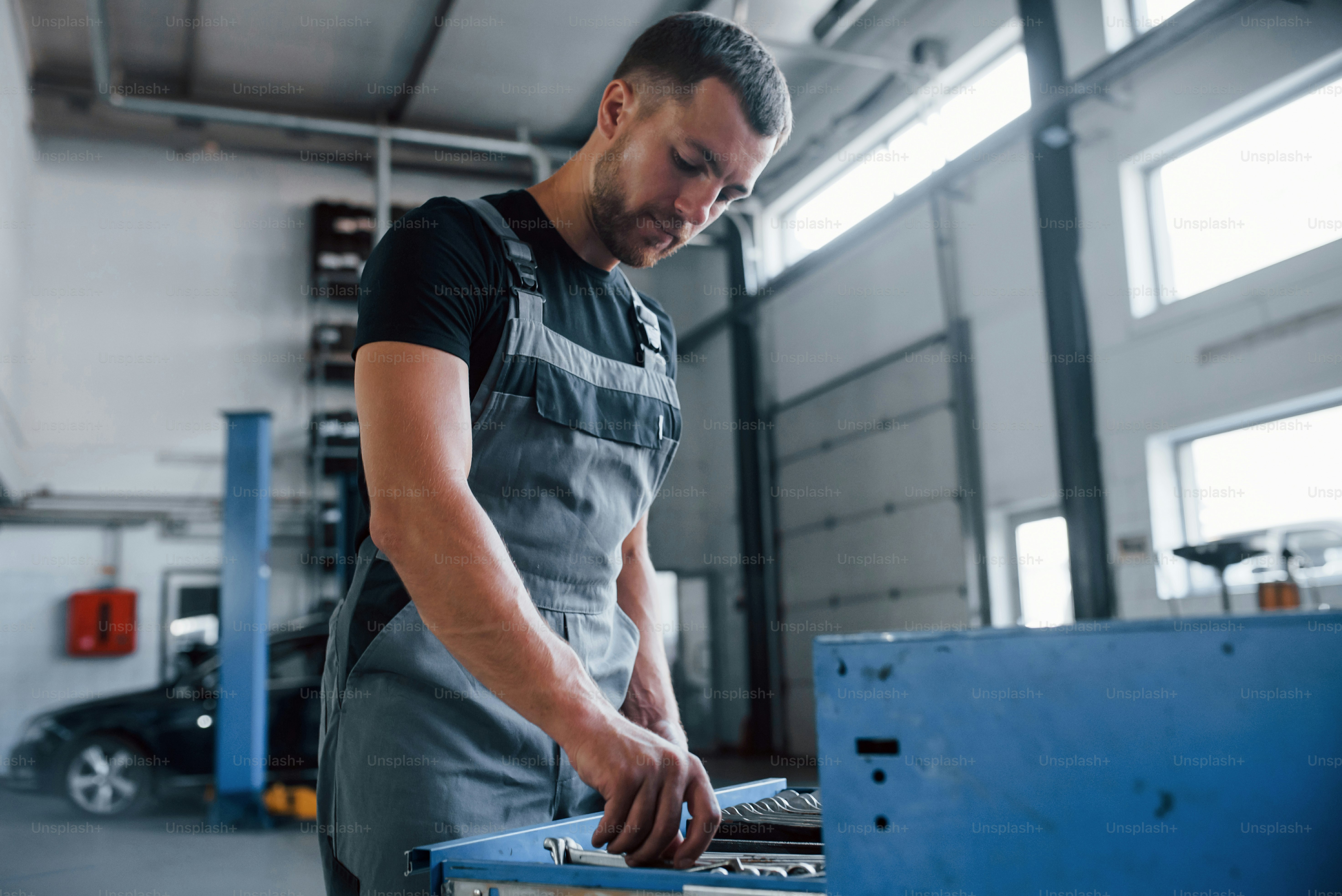 Blue colored drawer. Male mechanic use different tools to repair broken ...