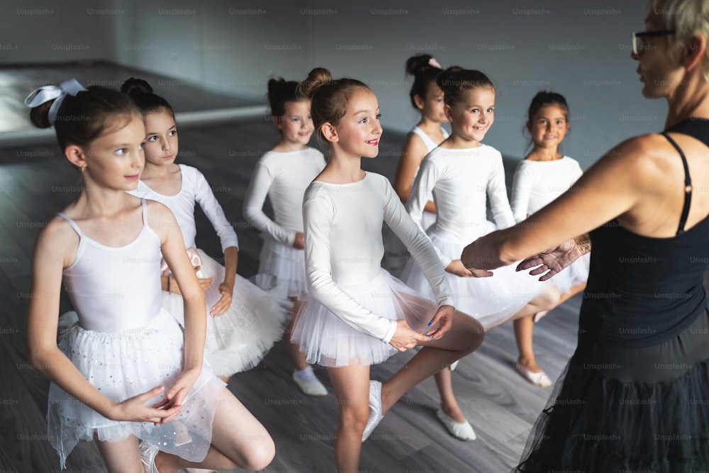 Ballet teacher and students ballerinas exercising in dance class