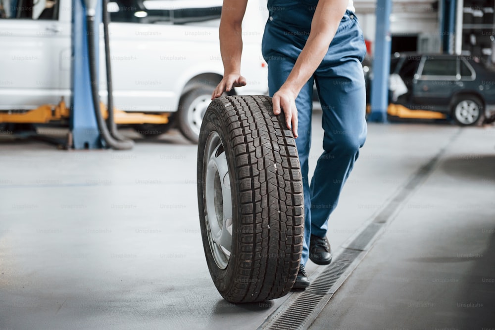 Rolling on the floor. Employee in the blue colored uniform works in the automobile salon.