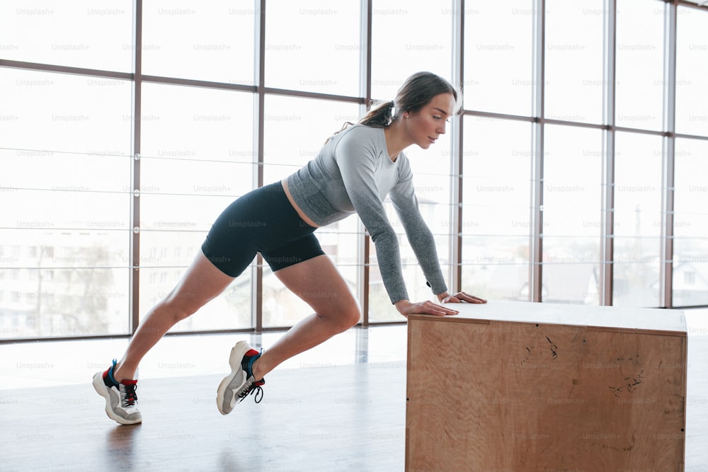 In black shorts and grey shirt. Sportive young woman have fitness day in the gym at morning time.