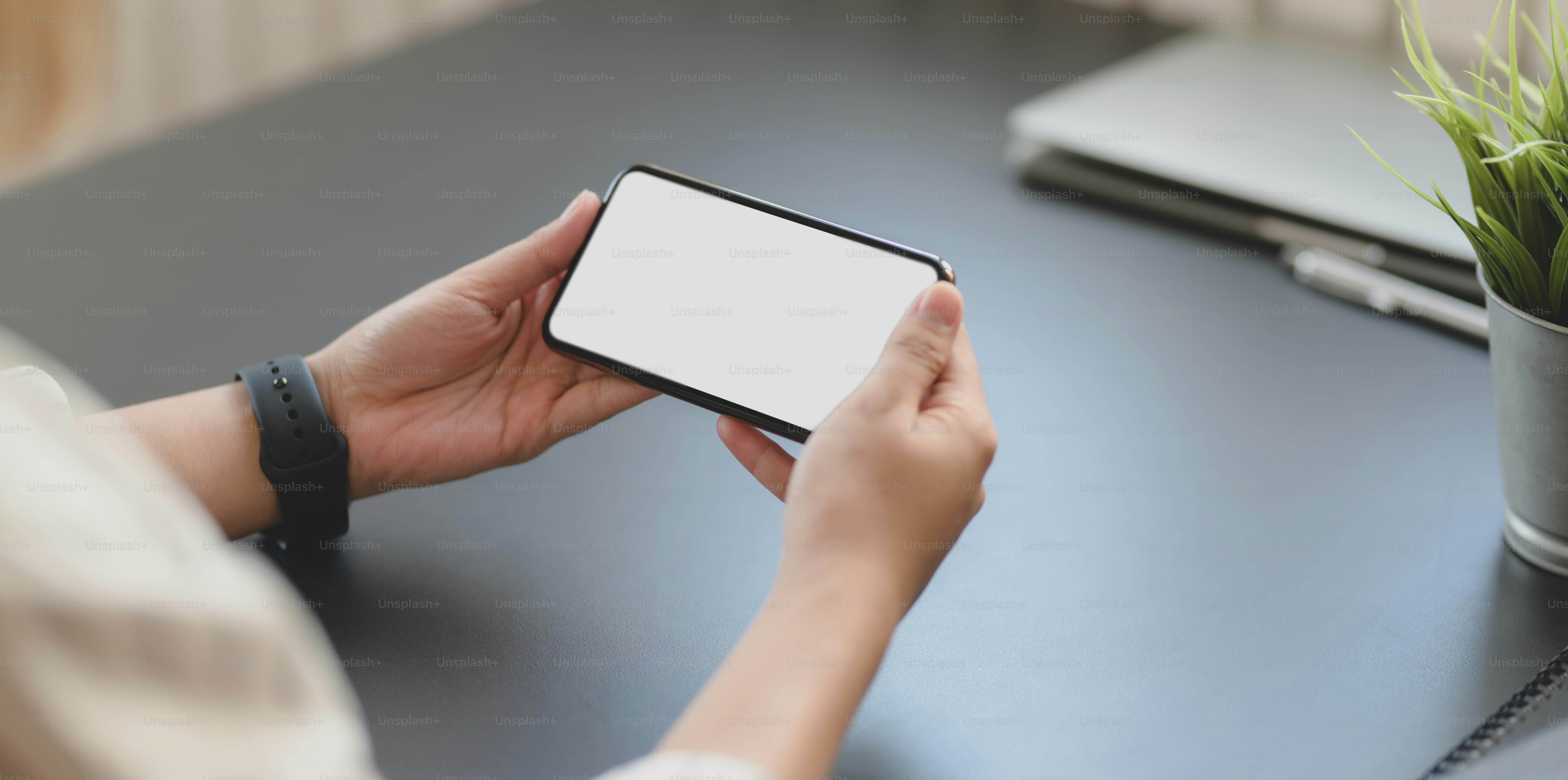 Cropped shot of professional businesswoman holding horizontal blank screen smartphone in his office room