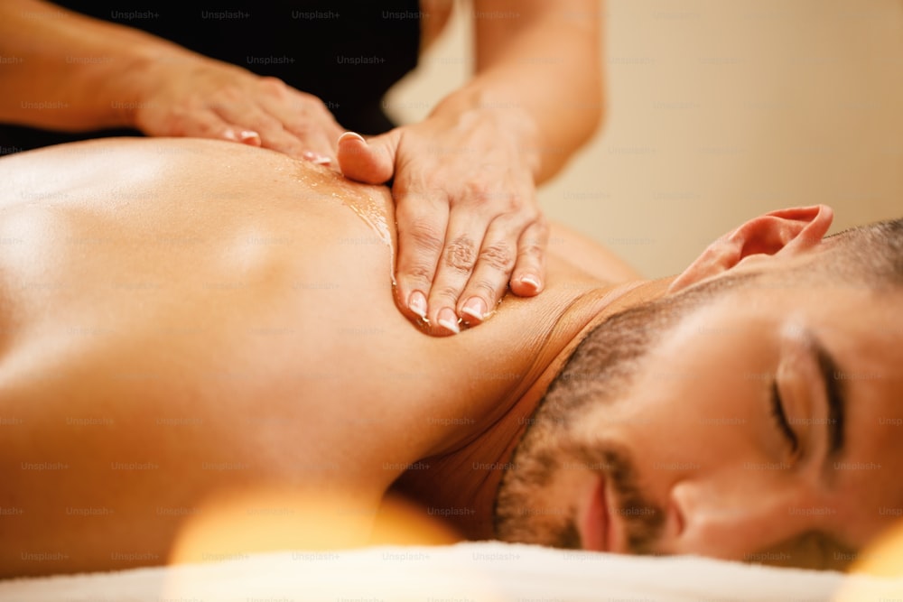Close-up of man enjoying in relaxing back massage with honey at the spa.