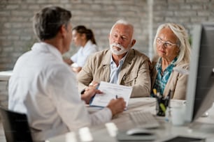 Casal sênior consultando com o profissional de saúde sobre sua apólice de seguro enquanto se reunia na clínica.