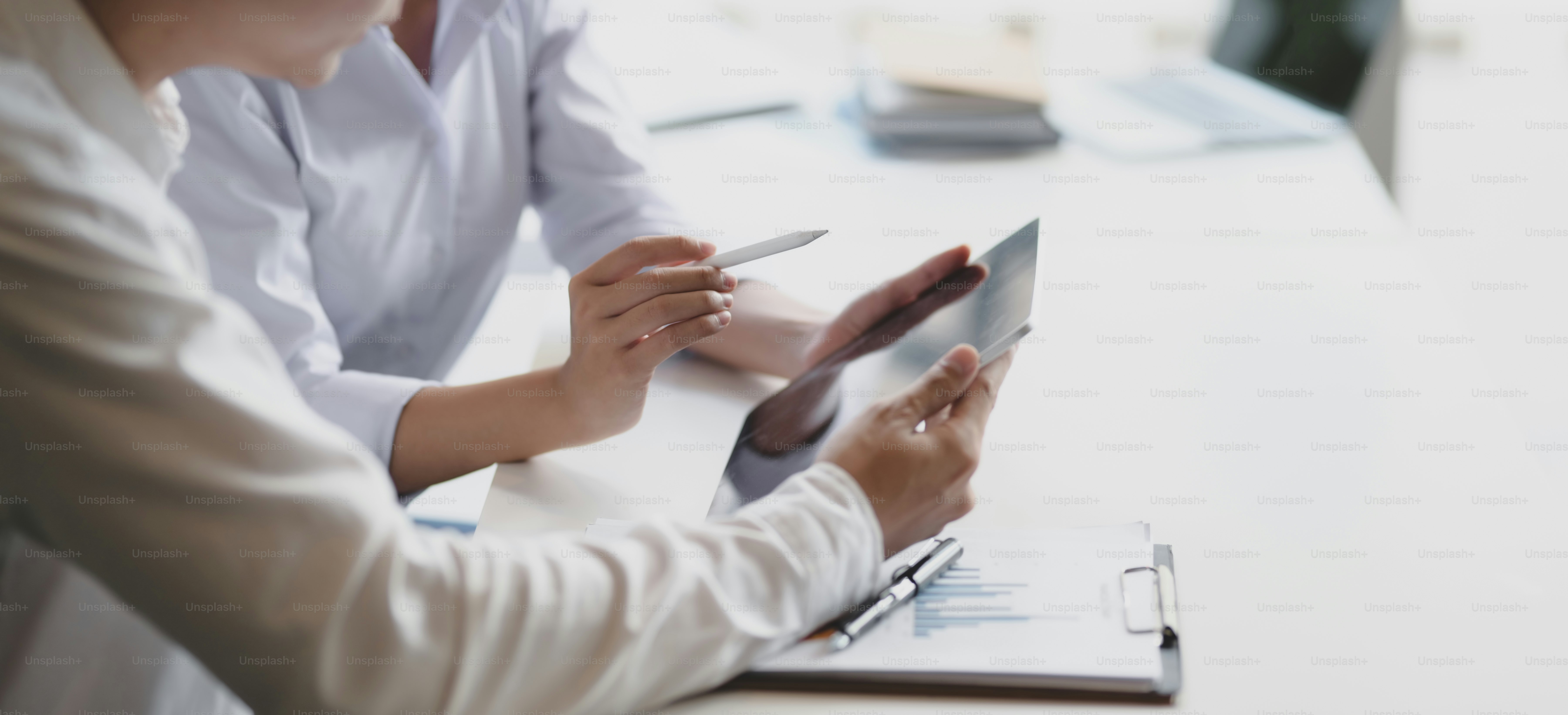 Cropped shot of two professional business partner discussing their project together while using tablet