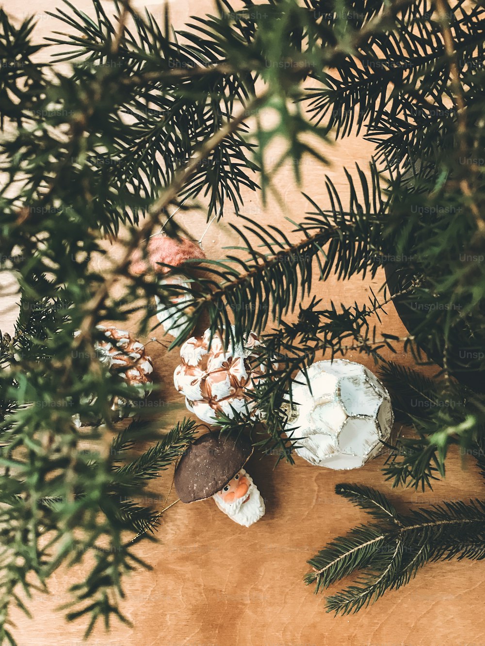 Enfeites de vidro vintage de Natal e brinquedos de cogumelos em mesa de madeira rústica sob galhos de abeto. Preparação para as férias de inverno. Decoração e arranjo festivos. Foto do telefone