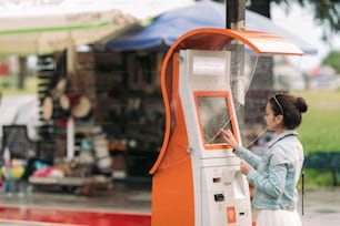 Una mujer turista compra billetes de transporte en Georgia. Máquina callejera moderna para la compra de billetes de autobús