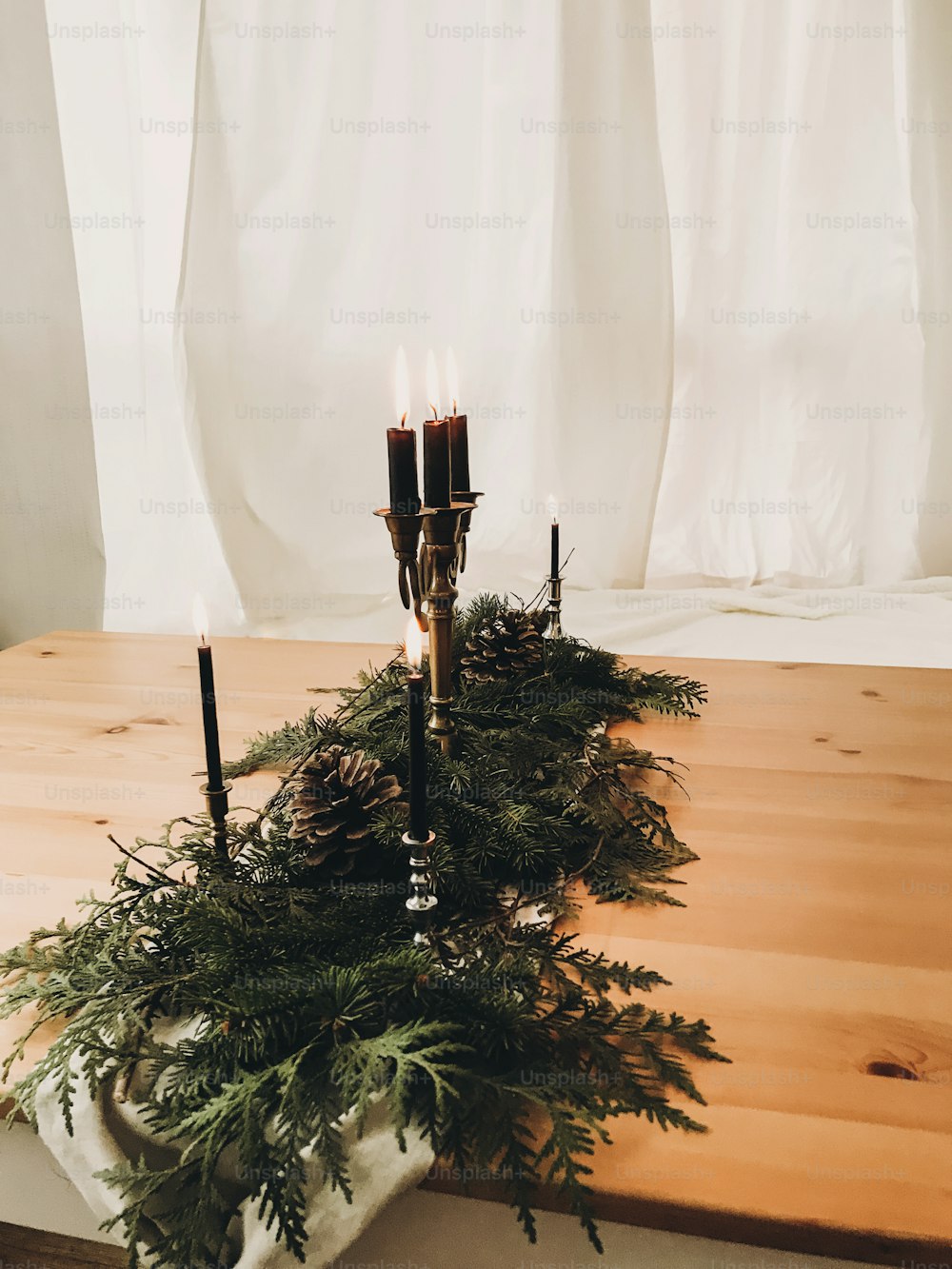 Christmas rustic decor of table. Vintage candlestick with burning candles,pine branches with cones on wooden table, festive arrangement. Rural holiday decoration. Phone photo