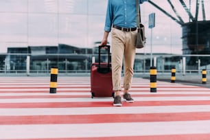 Male is carrying suitcase while walking on pedestrian crossing. Website banner