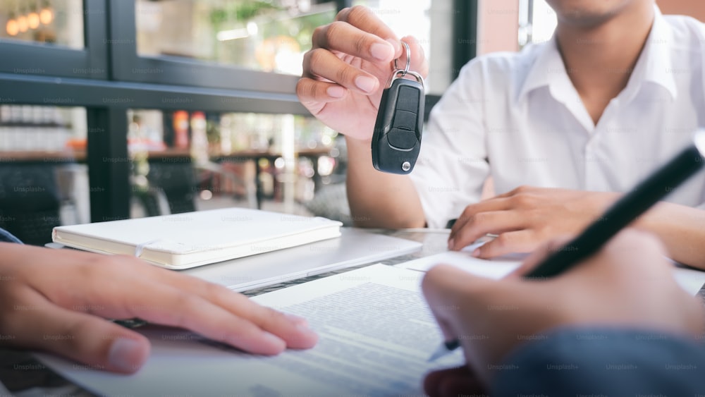 Business concept, car insurance, sell and buy car, car financing, car key for Vehicle Sales Agreement. New carowners are taking keys from male salespeople.