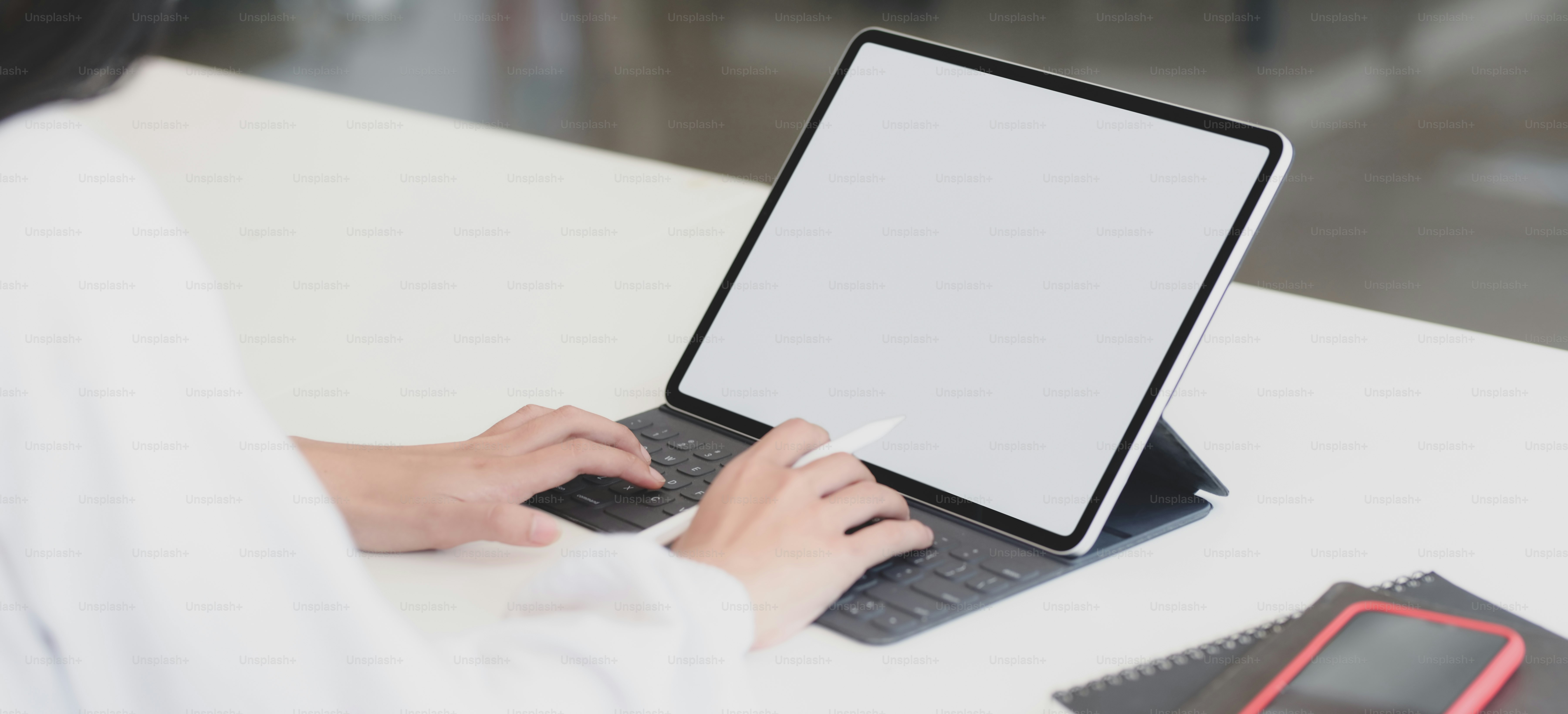 Cropped shot of young businesswoman working on her project while typing on tablet in modern office room