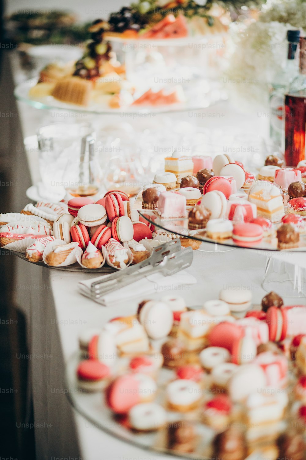 Delicious pink candy bar at wedding reception or christmas celebration. Pink and white macarons,cupcakes, desserts on stand, modern sweet table. Luxury catering concept