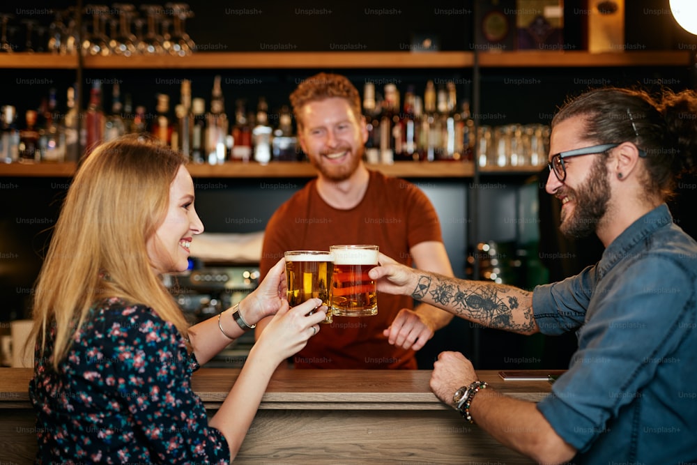 Caucasian couple standing in pub, toasting with beer and having fun. Nightlife.