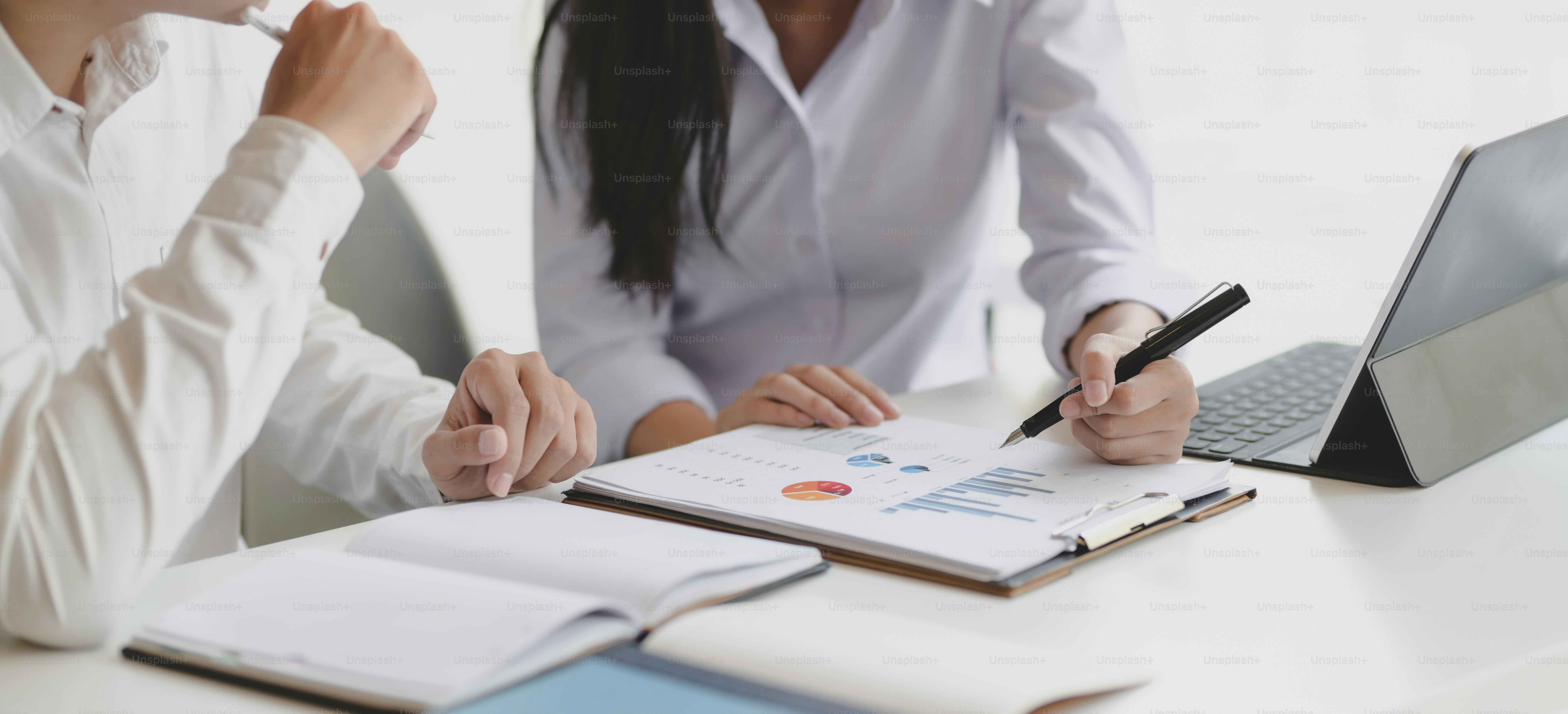 Cropped shot of two professional business partner discussing their project together while using graphs and charts