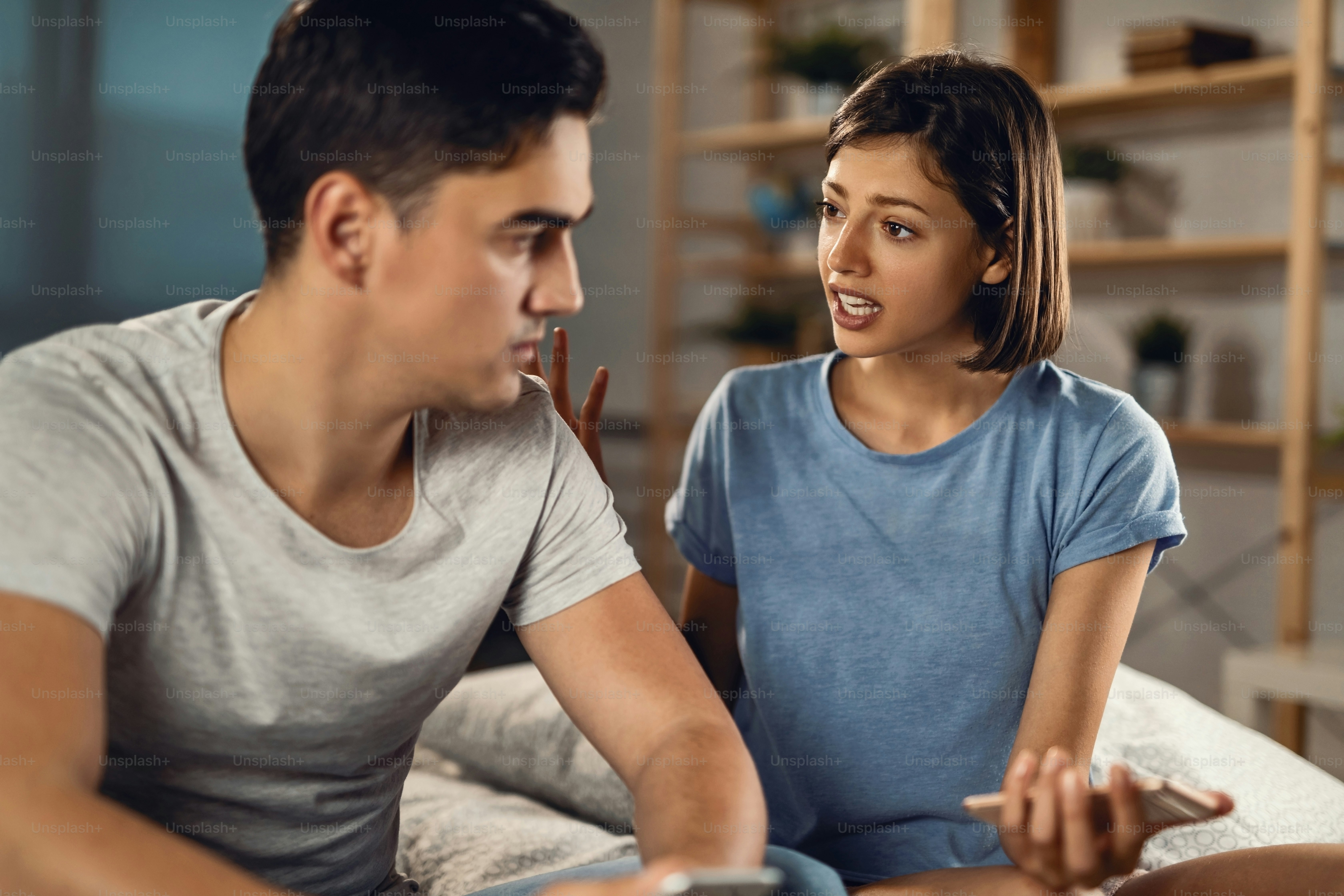 Young couple having a conflict and arguing in the bedroom. Focus is on woman.