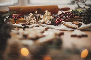 즐거운 성탄절. 아니스, 계피, 솔방울, 삼나무 가지, 황금빛 조명 보케를 곁들인 축제 진저브레드 쿠키가 소박한 테이블에 놓여 있습니다. 대기 이미지. 계절 인사말