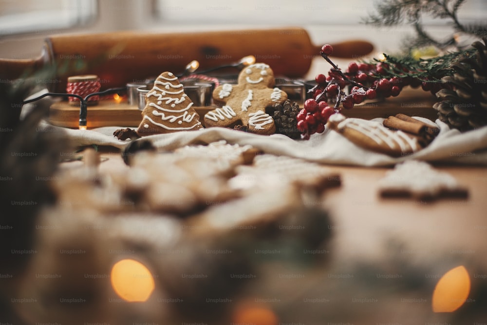 Merry Christmas. Festive gingerbread cookies with anise, cinnamon, pine cones, cedar branches and golden lights bokeh on rustic table. Atmospheric image. Seasons greetings