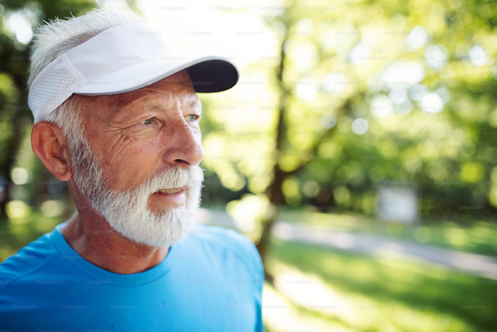 Attraktiver pensionierter Senior mit einem netten Lächeln beim Joggen im Park