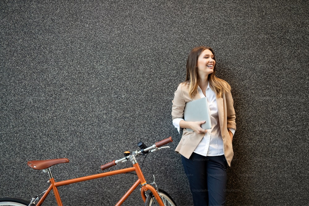 Young businesswoman standing in a city with bicycle and tablet