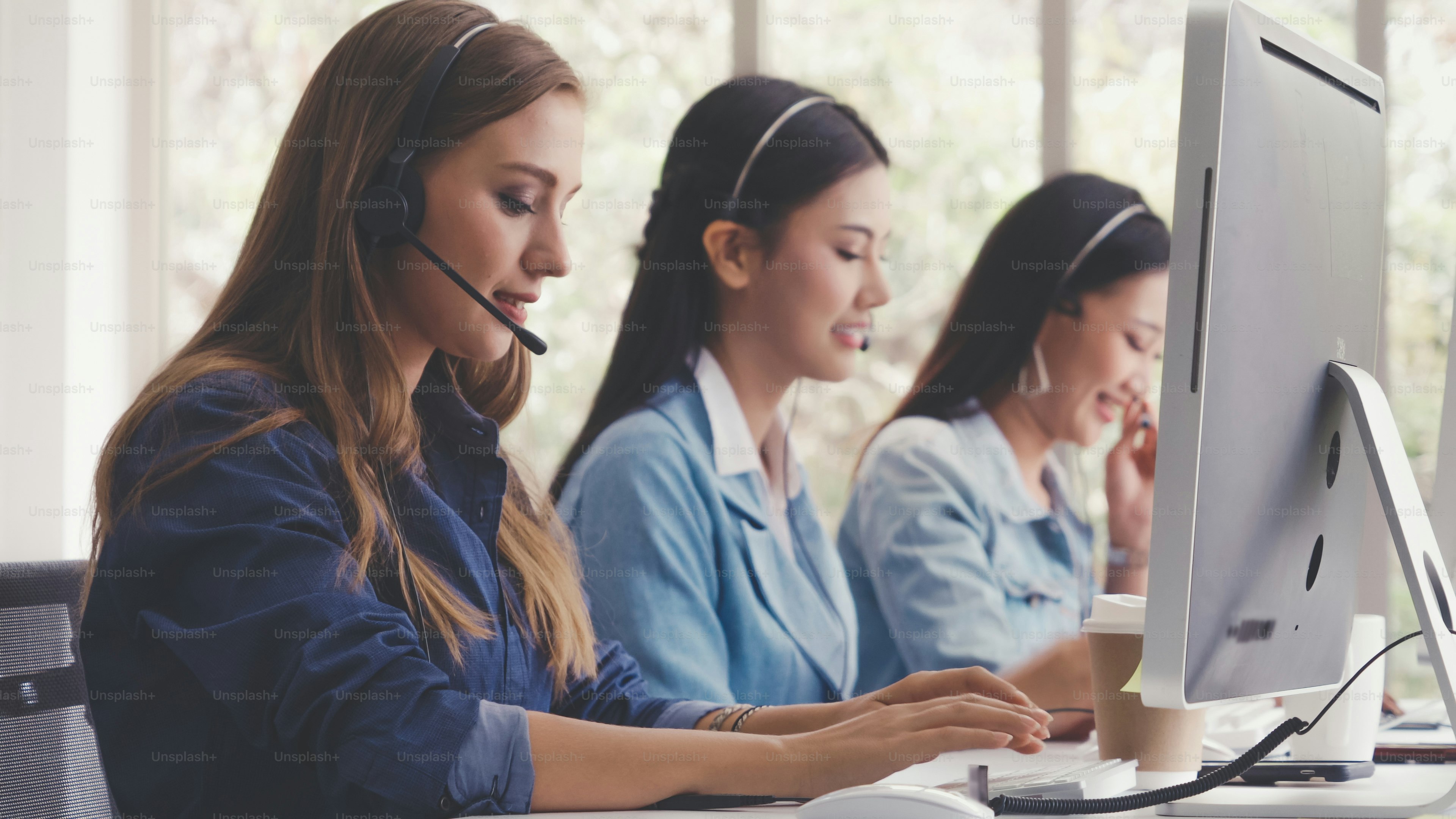 Customer support agent or call center with headset works on desktop ...