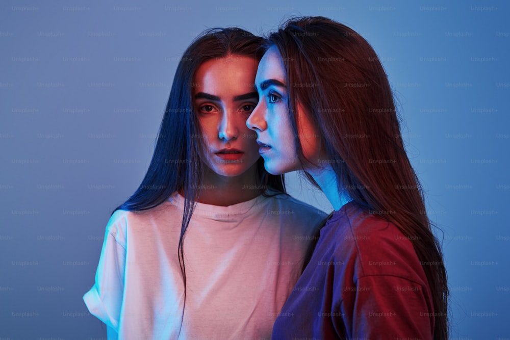 Handsome people. Studio shot indoors with neon light. Photo of two beautiful twins.