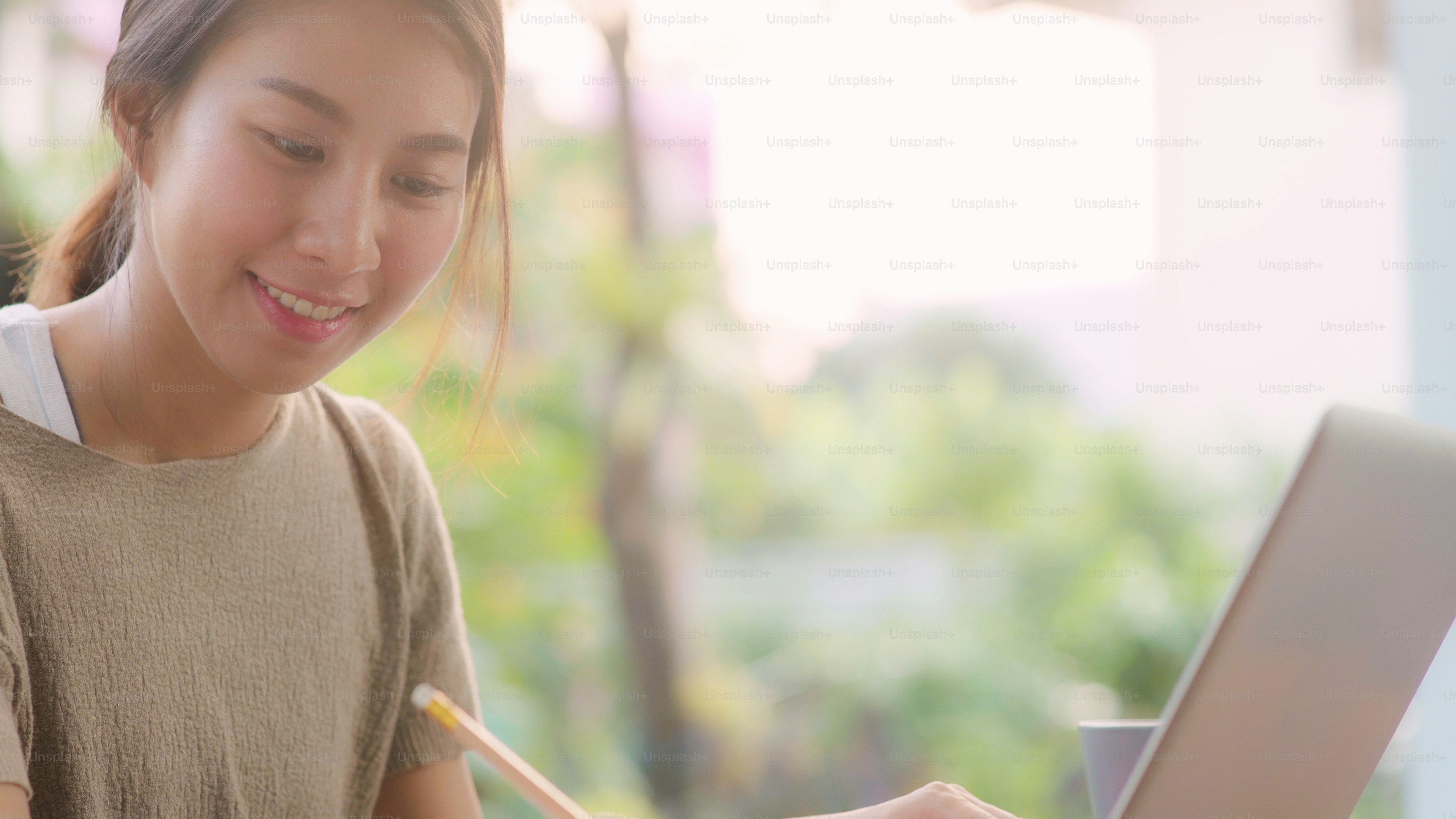 Freelance Asian woman working at home, business female working on laptop sitting on table in the garden in morning. Lifestyle women working at home concept.