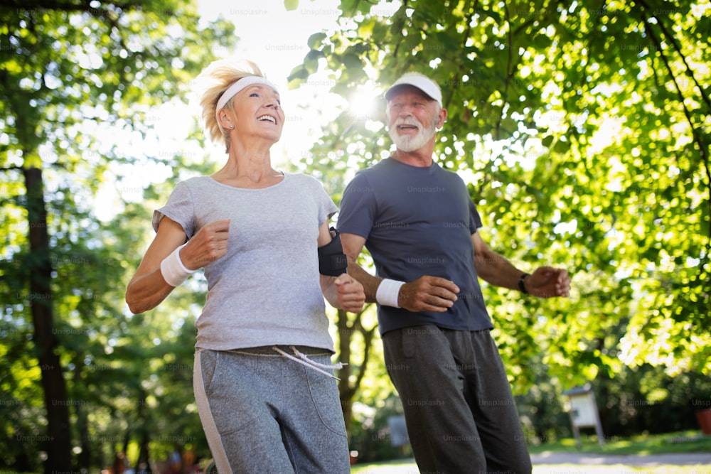 Beautiful senior couple running outside in sunny forest