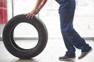 Cropped photo. Woman walks with brand new wheel to the car. Conception of repair.