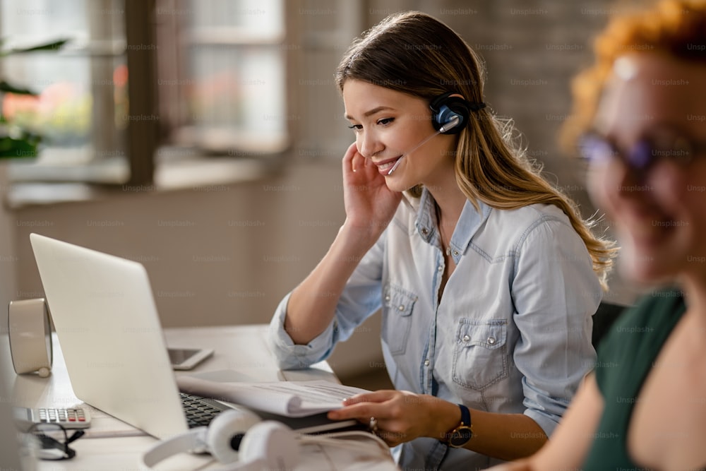 Operador de servicio al cliente sonriente con auriculares que hablan con un cliente mientras trabaja en el centro de llamadas.