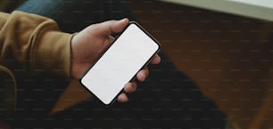 Close-up view of man holding blank screen smartphone while sitting his comfortable office room