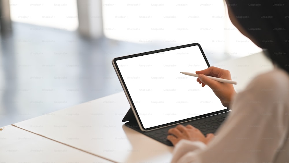 Young creative woman holding stylus pen and working with mockup tablet, Empty screen device.