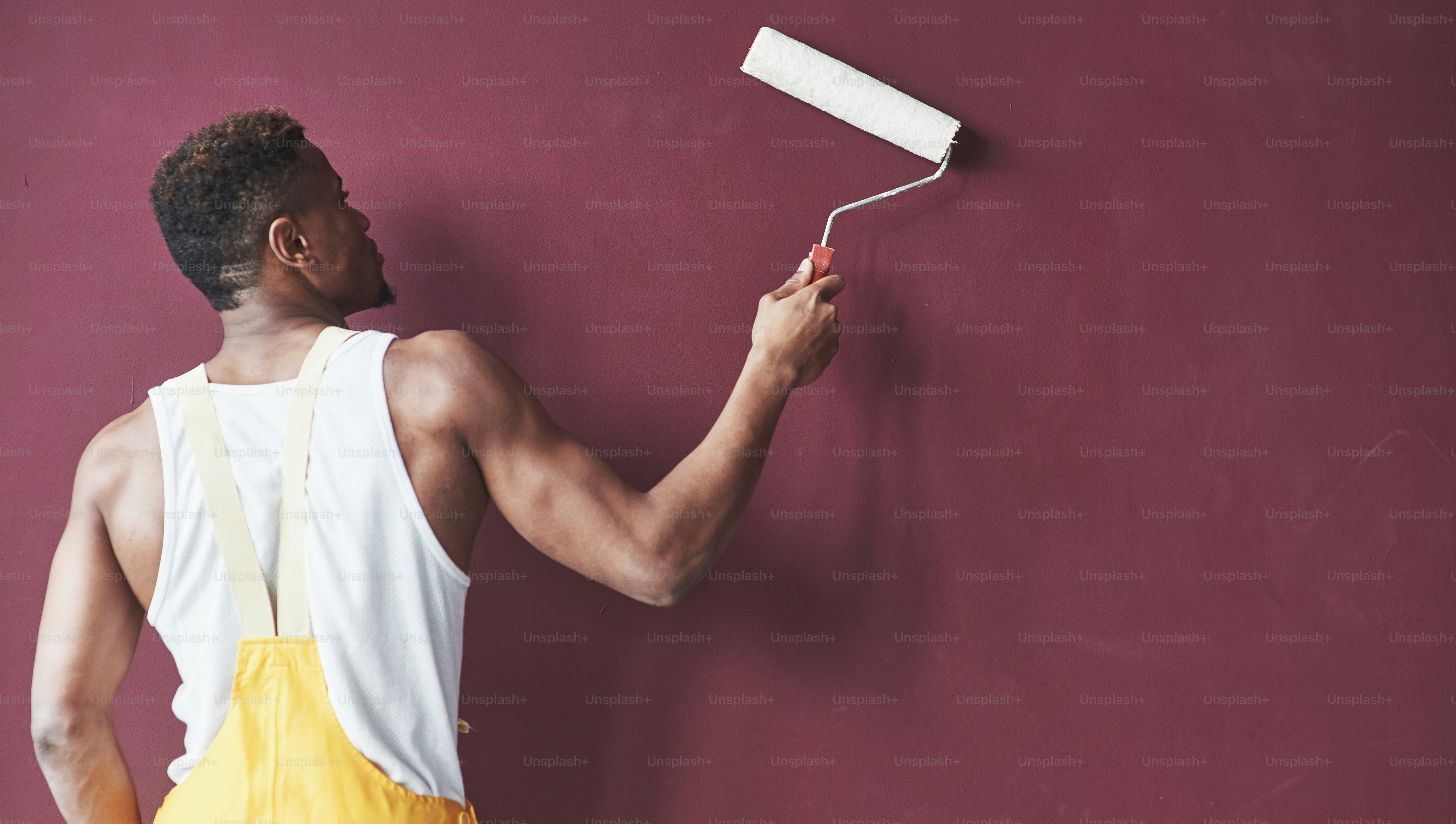 背面図。黄色い制服を着た若いアフリカ系アメリカ人労働者は、いくつかの仕事をしています。