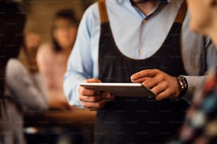 Close-up of unrecognizable waiter using touchpad in a bar.