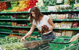 Vegetables and fruits. Female shopper in casual clothes in market looking for products.