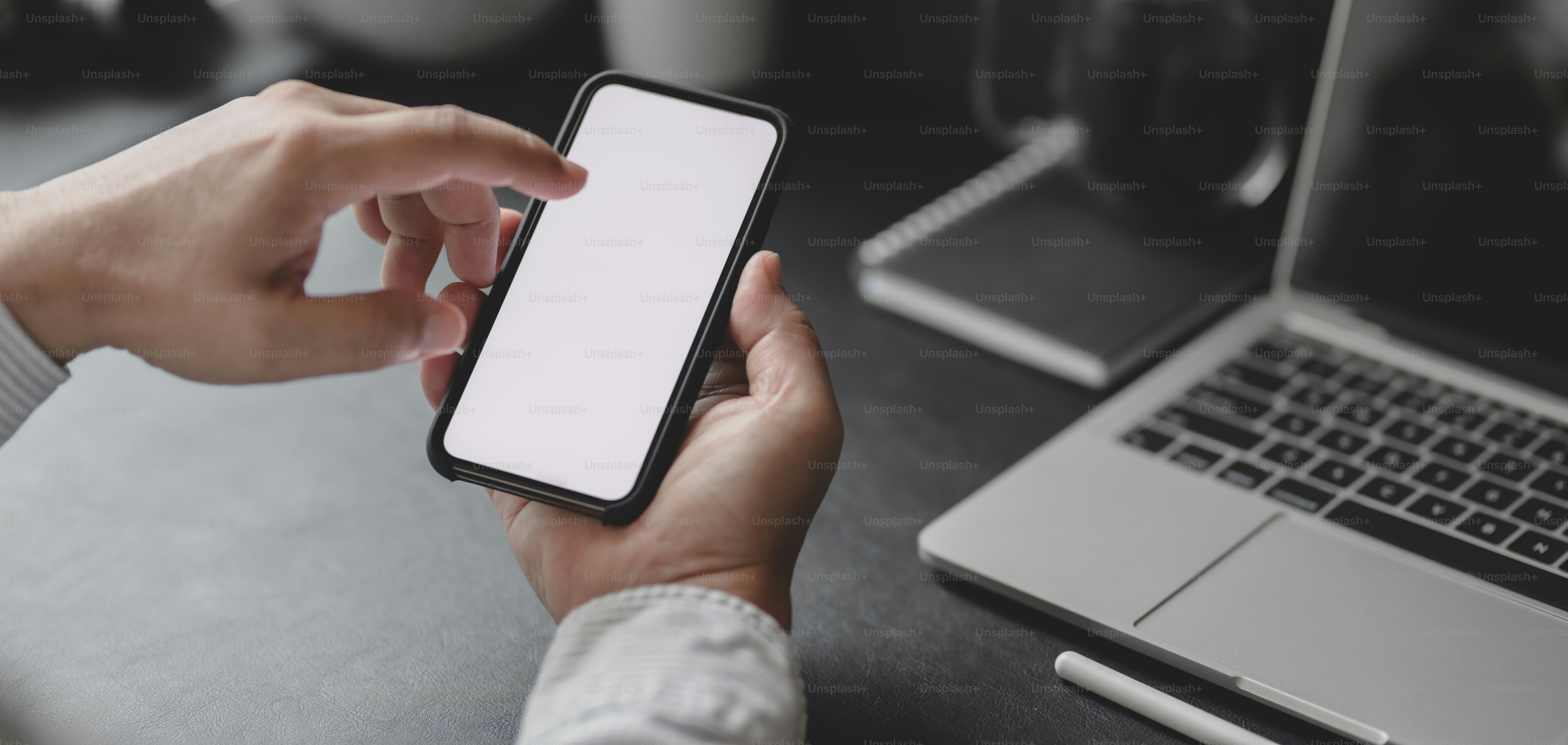 Cropped shot of professional businessman using blank screen smartphone in dark modern office room