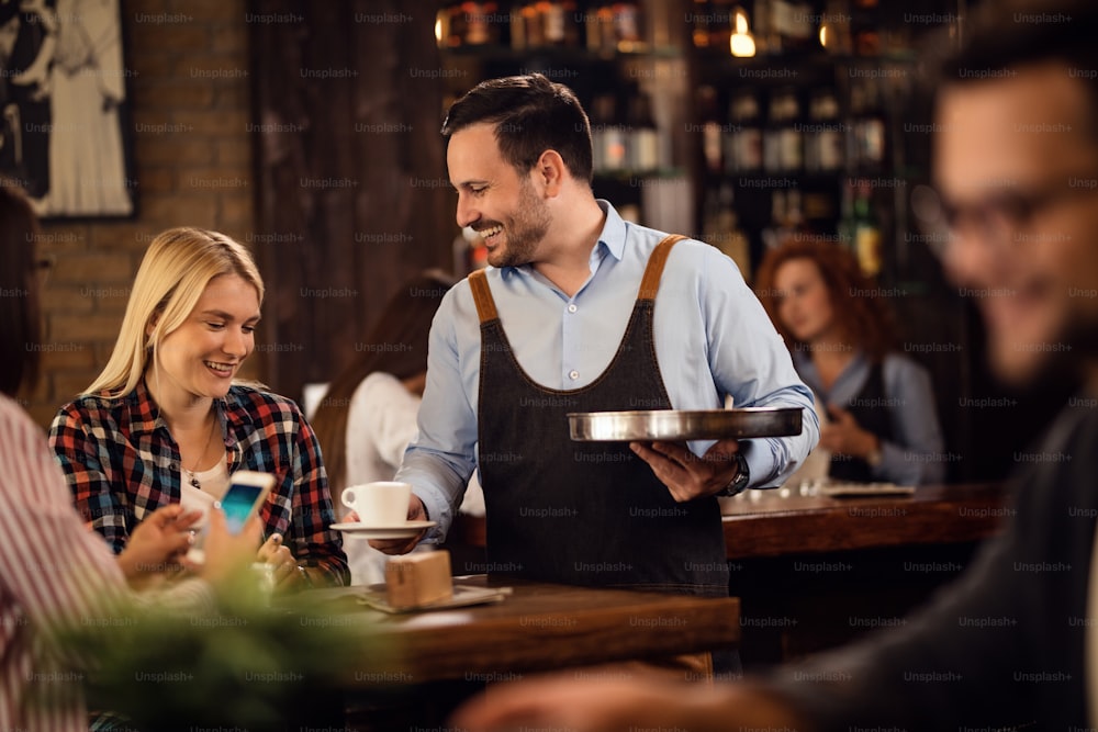 Young happy woman enjoying while waiter is serving her coffee in a cafe.