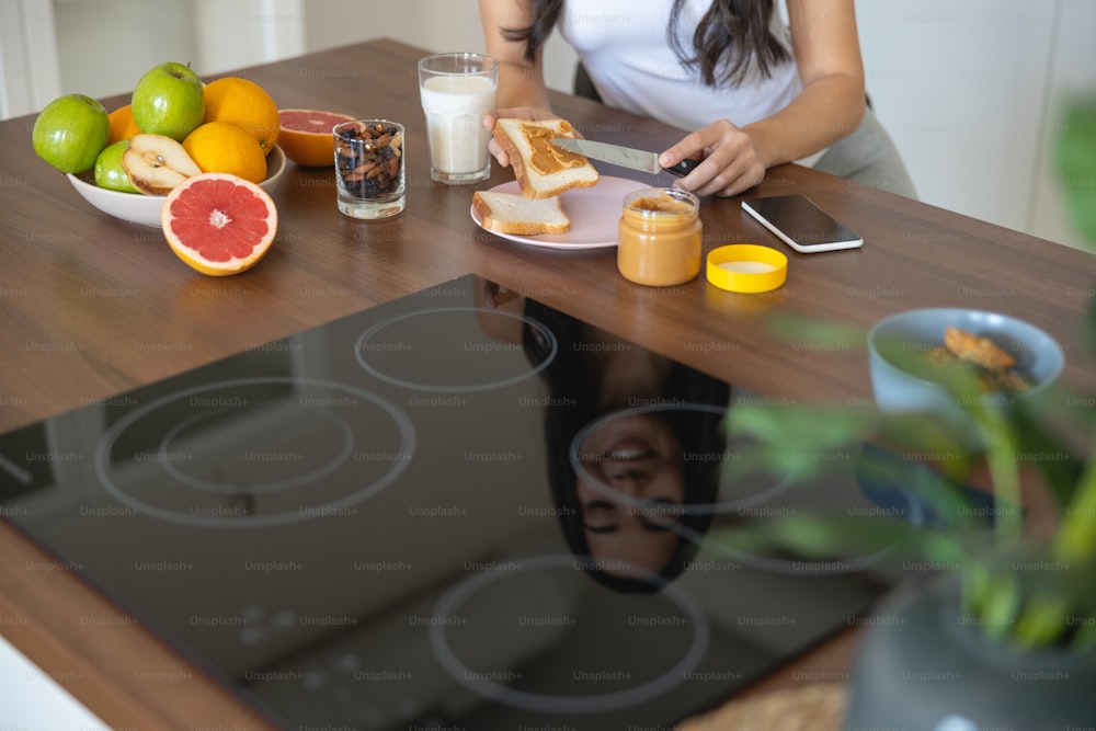 Cropped photo of a lady spreading peanut butter with a knife