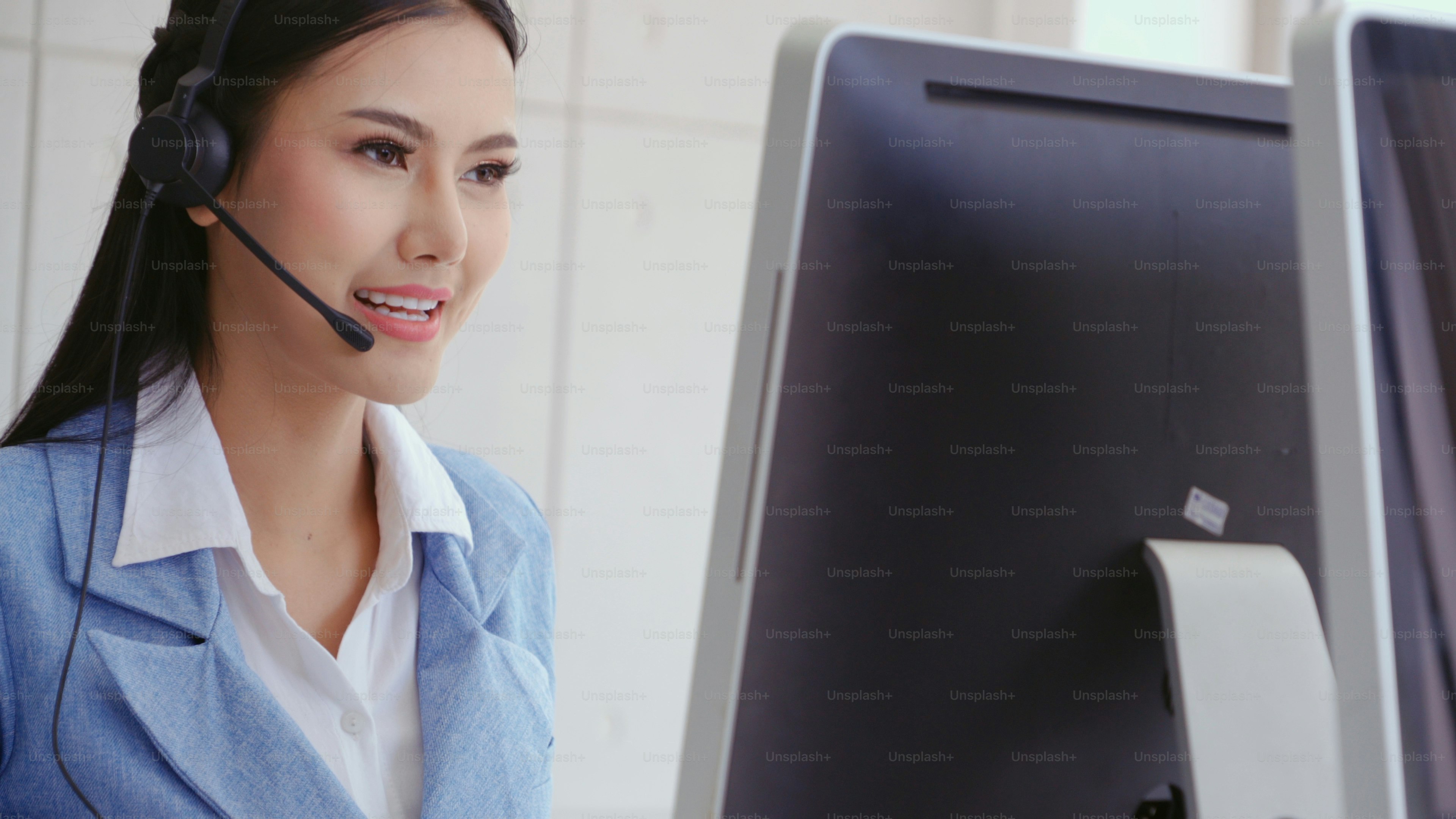 Customer support agent or call center with headset works on desktop computer while supporting the customer on phone call. Operator service business representative concept.