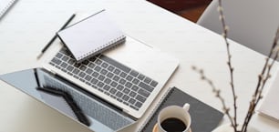 Abgeschnittene Aufnahme eines modernen Büroraums mit Laptop und Bürobedarf auf weißem Holztisch